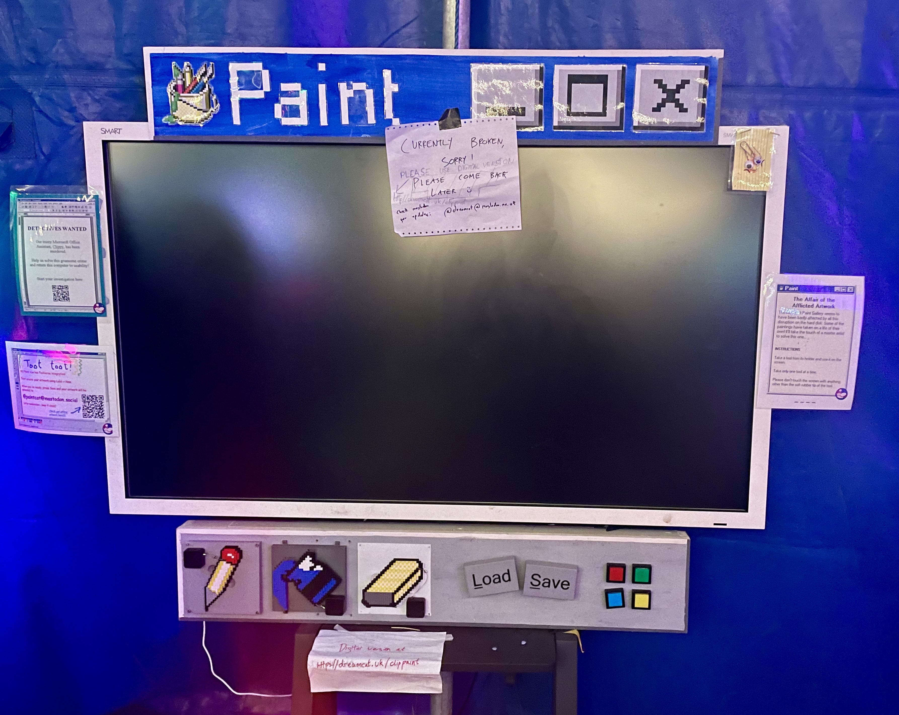 A real-life version of Microsoft Paint, complete with Windows toolbars and pixel-style tools. There is a screen that is switched off and a sign saying that the installation is currently broken.